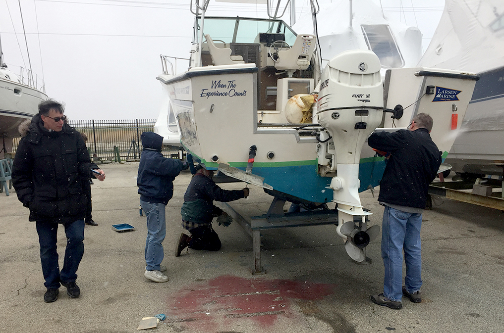 volunteers sand and paint the committee boat